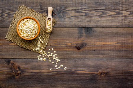 Cook oatmeal. Cereals in bowl and scoop on dark wooden background top view.の素材 [FY31096029892]