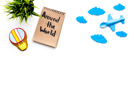 Family trip concept. Airplan toy, air balloon cookie. Around the world hand lettering in notebook on white background top view.の写真素材