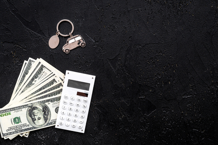 Car credit concept. Money and calculator near keychain in shape of car silhouette on black background top view.の写真素材