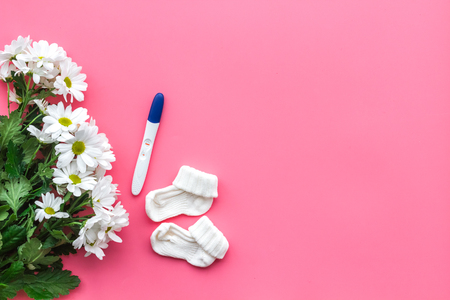 Joy of long-awaited pregnancy. Pregnancy test with two stripes near flowers on pink background top view copy spaceの写真素材