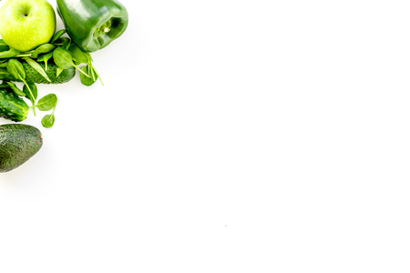Green vegetables background. Shiny bell pepper, cucumber, arugula salad, avocado and fresh apple on white background top view copy spaceの写真素材