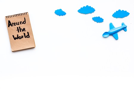 Family trip concept. Airplan toy, clouds. Around the world hand lettering in notebook on white background top view copy spaceの写真素材