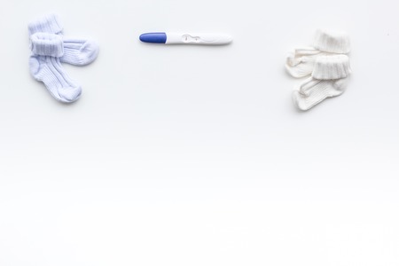Pregnancy and preparation for childbirth. Pregnancy test near booties on white background top view.の写真素材