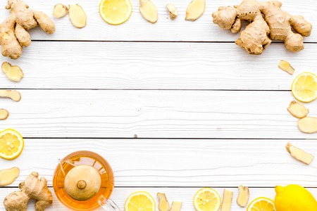 Ingredient for warming tea. Whole and sliced ginger roots, lemon on white wooden background top view copy spaceの写真素材