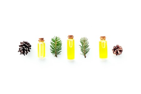 Pine essential oil in bottles on white background top view copy space. Pattern with pine branch and cone.の写真素材
