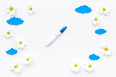 Pregnancy and preparation for childbirth. Pregnancy test near booties on white background top view.