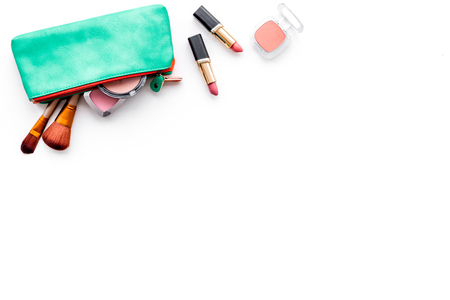 Decorative cosmetics background. Eyeshadow, rouge, brushes, lipstick in cosmetic bag on white top view copy spaceの写真素材