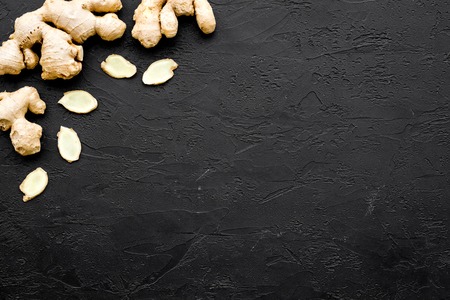 Whole and sliced ginger roots on black background top view.の写真素材
