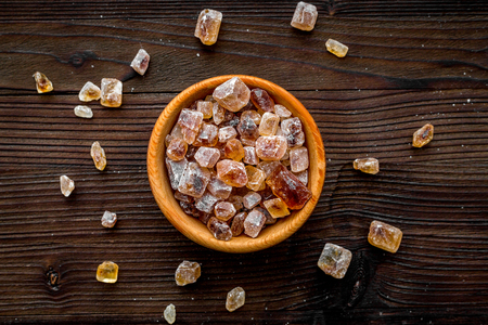 Types of sugar. Candy brown sugar in bowl on dark wooden background top view.の写真素材