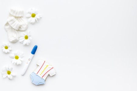 Pregnancy and preparation for childbirth. Pregnancy test near booties on white background top view.の写真素材