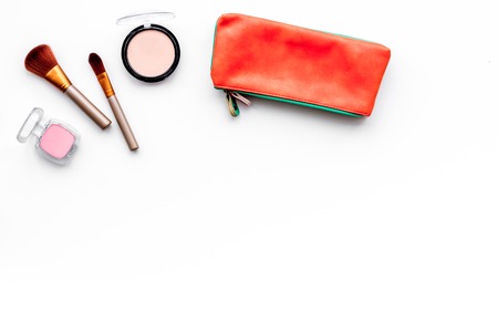 Decorative cosmetics background. Eyeshadow, rouge, brushes, lipstick in cosmetic bag on white top view.の写真素材