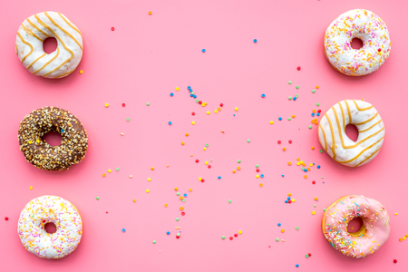 Donuts decorated icing and sprinkles on pink background top view patternの写真素材