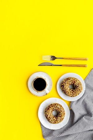 breakfast with coffee, donuts and flowers on yellow background top view mockupの写真素材