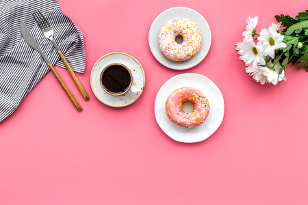 breakfast with coffee, donuts and flowers on pink background top view mockup