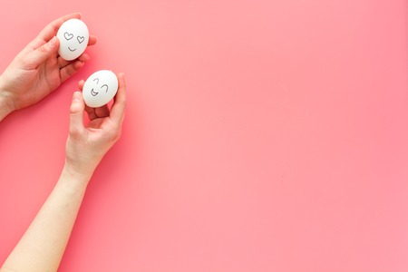 Emotion management concept. Fallen in love and happy. Face drawn on egg. Pink background top view copy spaceの写真素材