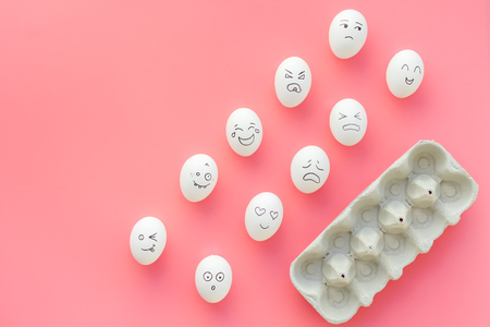 Basic emotions concept. Faces drawn on eggs. Happy, smile, sad, angry, in love. Pink background top view copy spaceの写真素材