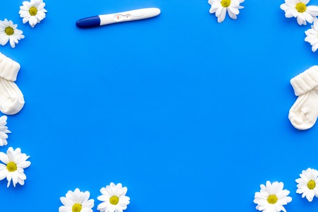 Pregnancy and preparation for childbirth. Pregnancy test near flowers on blue background top view space for text.の写真素材