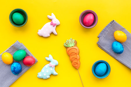 Sweets for celebrate Easter. Gingerbread in shape of easter bunny and easter eggs. Yellow background...