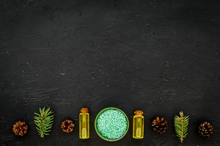 Pine essential oil in bottles on dark background top view copy space. Pattern with pine branch and cone.の写真素材