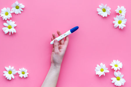 Waiting for a baby with positive pregnancy test and flowers on pink background top view mockupの写真素材