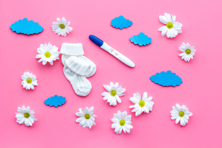 Pregnancy test, socks and flowers on pink background top viewの写真素材