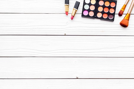 Decorative cosmetics set with eyeshadow, lipstick, brushes on white desk background top view copy spaceの写真素材