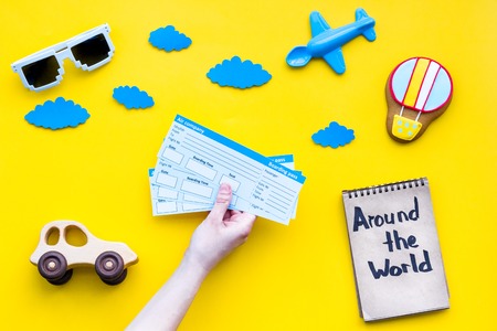 Travelling with child concept. Air balloon, car and plane. Around the world hand lettering in notebook on yellow background top view copy spaceの写真素材