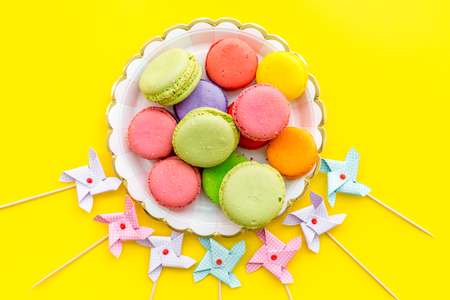 Sweets for party background. Macaroons and lollipop on yellow background top view.の写真素材