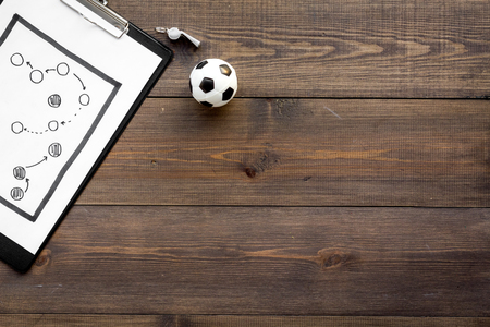 Sport coach concept. Pad with tactic plan of the match near whistle and football ball on wooden background top view copy spaceの写真素材