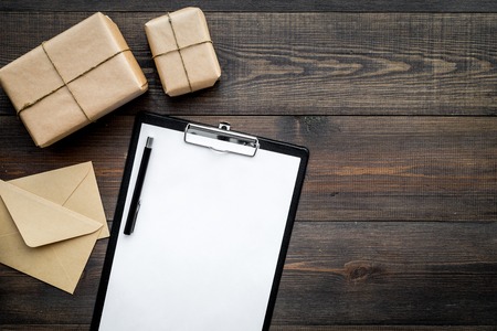 Courier workplace with cardboard box and letters for delivery on wooden desk background top view mockupの写真素材