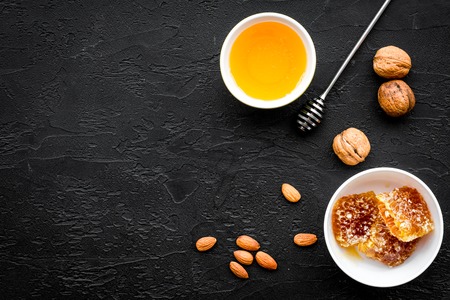 Fresh honey as dessert. Honey in bowl, honeycomb, nuts on black table top view.の写真素材