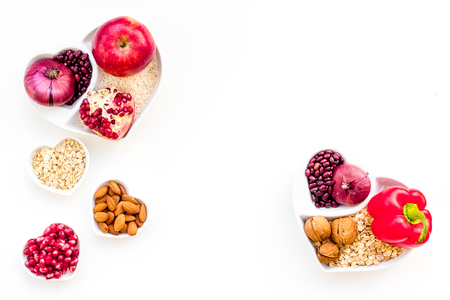 Diet for healthy heart. Food with antioxidants. Vegetables, fruits, nuts in heart shaped bowl on white background top view.の写真素材