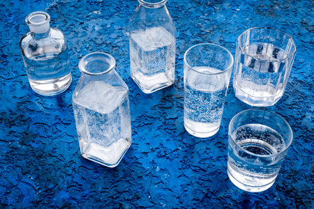 Drinks on the table. Pure water in jar and glasses on blue background.