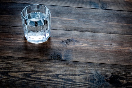 Glass of pure water on dark wooden background top view.の写真素材