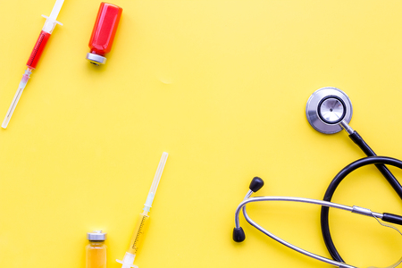 Medical examination and treatment concept. Stethoscope, syringe on yellow background top view.の写真素材
