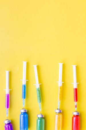Vaccination, immunization. Syringe and bottle with medicament on yellow background top view copy spaceの写真素材