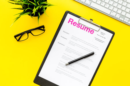 Empoyment concept. Resume on pad near pen and glasses on yellow background top view