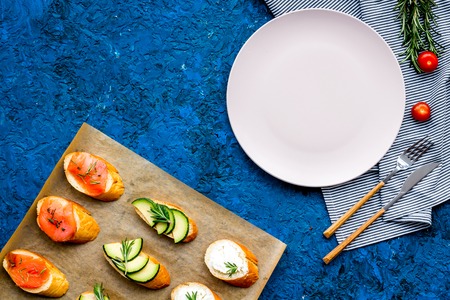 Healthy lunch with mini sandwiches cheese, fish and avocado on blue kitchen table background top view space for textの写真素材