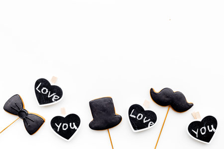 Men's birthday concept. Cookies in shape of moustache, hat, bow tie. Hearts with lettering love you on white background top view.の写真素材