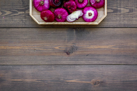 Red onion is healthy product. Onion bulbs in tray on dark wooden background top view.の写真素材