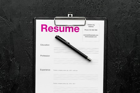 Empoyment concept. Resume on pad near pen and glasses on black background top view.の写真素材