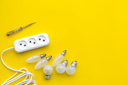 Electrical installation, wiring works. Bulbs and socket outlet on yellow background top view copy spaceの写真素材