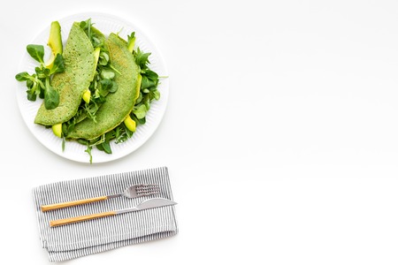 Spinach pancakes with spinach leaves and avocado slices on plate on white background top view copy spaceの写真素材