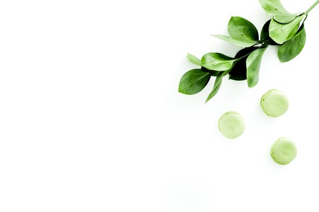 Summer background with green leaves and sweets macarons on white top view copy spaceの写真素材