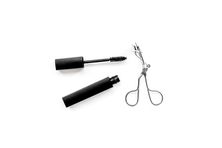 Basic products for eyelashes makeup. Mascara and eyelash curler on white background top view.