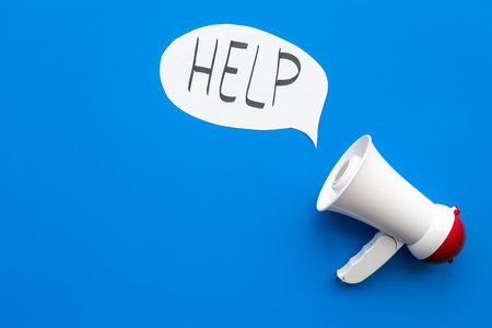 Call for help concept. Megaphone near cloud with word help on blue background top view.の写真素材