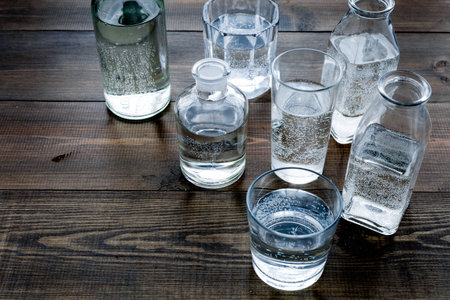 Drinks on the table. Pure water in jar and glasses on dark wooden background.