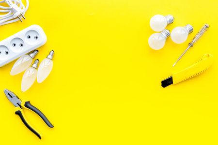 Electrical repair. Bulbs, socket outlet, cabel on yellow background top view.