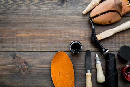 Tools for shoe repair on dark wooden background top view.