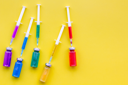 Vaccination, immunization. Syringe and bottle with medicament on yellow background top view copy spaceの写真素材
